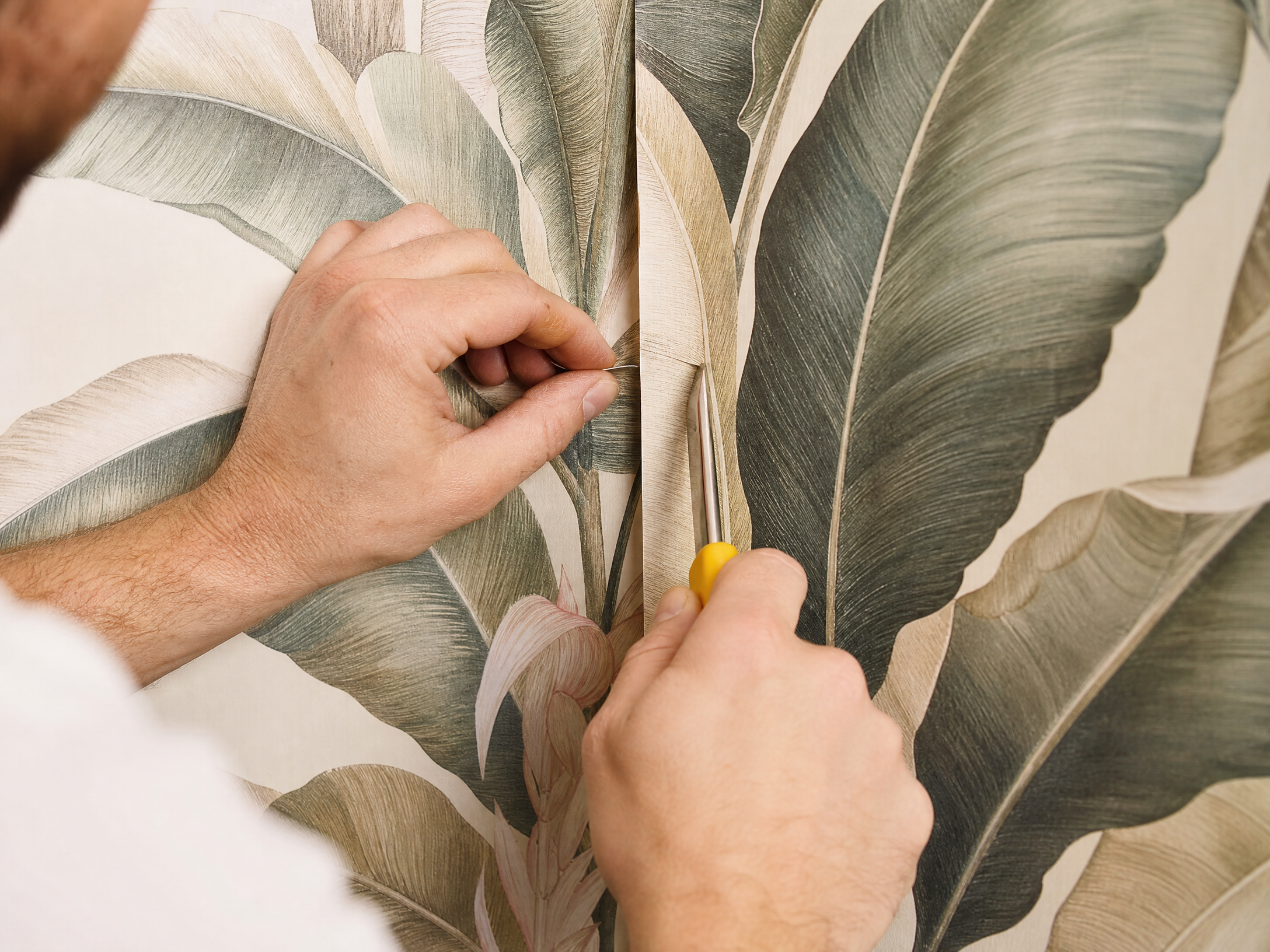 Close-up of a professional installer carefully aligning a seam on a botanical print wallpaper (placeholder image)